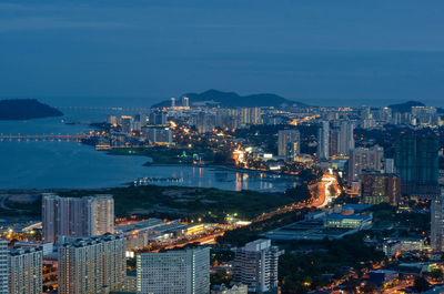 High angle view of illuminated city by sea against sky