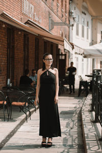 Full length portrait of young woman walking in city