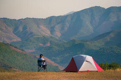 Rear view of man sitting on tent