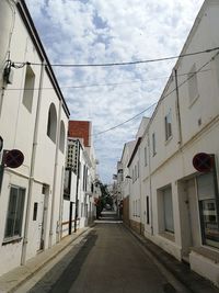 Empty road amidst buildings against sky