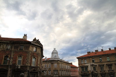 Low angle view of buildings against cloudy sky