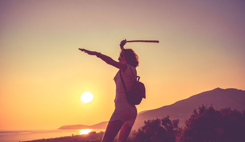 Side view of woman standing against clear sky during sunset