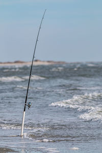 A fishing pole waits along the ocean surf coast