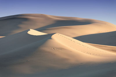 Scenic view of sand dunes against sky