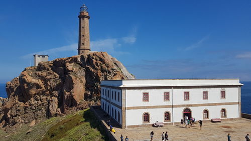 Group of people in front of historical building against blue sky