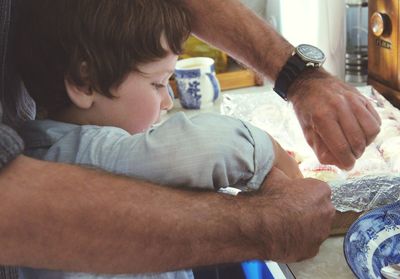 Father teaching son food preparation at kitchen