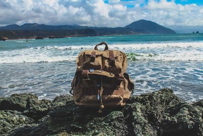 Backpack on rock against sea