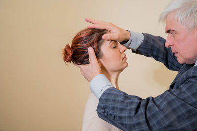 Portrait of man treating female patient against wall