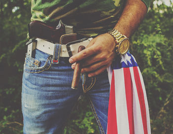 Midsection of man holding cigar outdoors