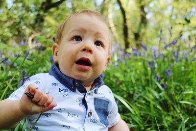 Close-up of baby boy by grass looking away