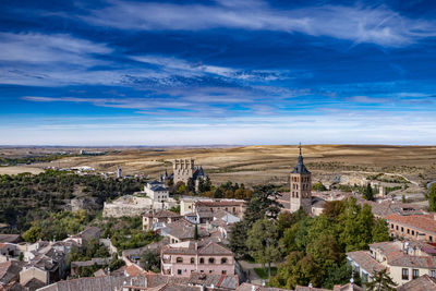 Aerial view of buildings in town against cloudy sky