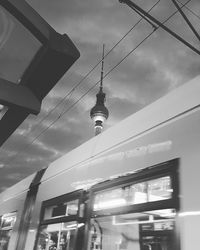 Low angle view of communications tower against cloudy sky