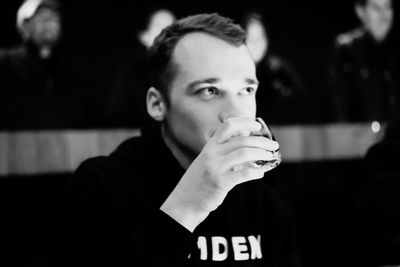 Young man looking away while drinking drink at home