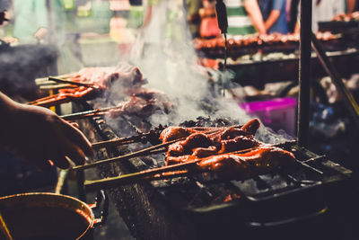 Person preparing food on barbecue grill