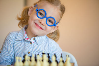 Portrait of smiling girl wearing eyeglasses standing by wall