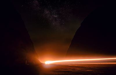 Light trails in sea against sky at night