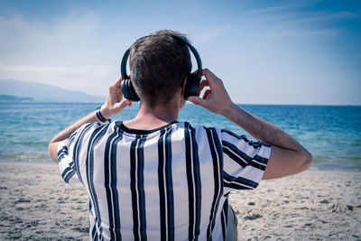 Rear view of man on beach against sky