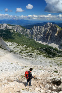 Man standing on rock by mountains against sky