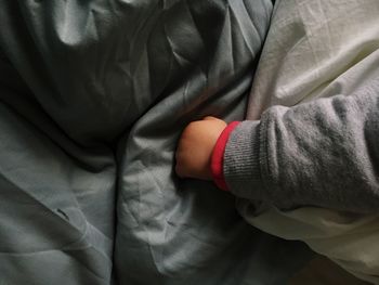 Cropped hand of baby girl on bed at home