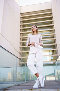 Portrait of young woman standing against building