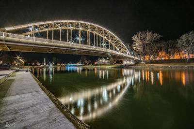 Illuminated bridge over river against sky at night