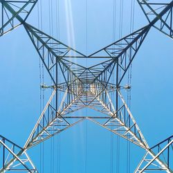 Low angle view of electricity pylon against clear blue sky