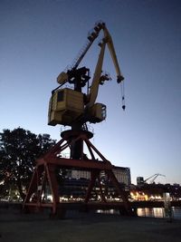 Low angle view of crane against clear blue sky