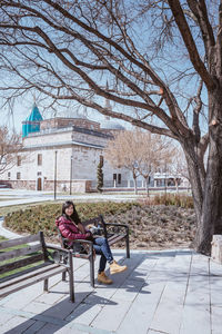 Rear view of woman sitting on bench in park