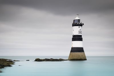 Lighthouse by sea against sky