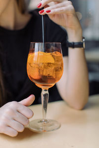 Midsection of woman with drink at table