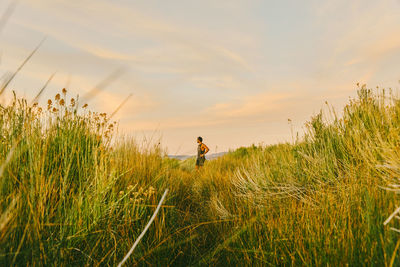 Man standing on field against sky during sunset