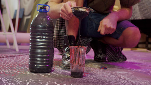 Low section of man holding glass jar on table