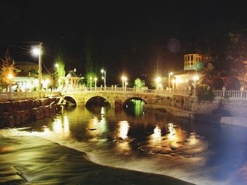 Illuminated bridge over river in city at night