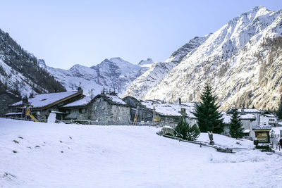 Snow covered houses and mountains against clear sky