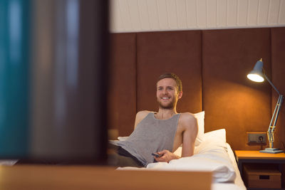 Happy man watching tv on bed