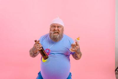 Portrait of man holding ice cream against pink background