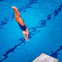 High angle view of mid adult woman jumping in swimming pool