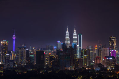 Illuminated buildings in city against sky at night