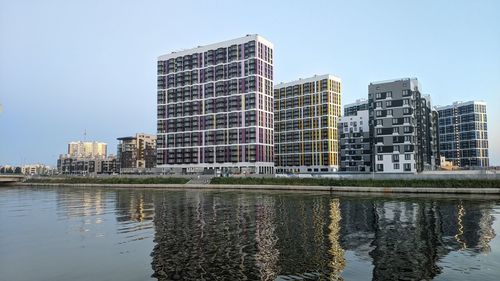 Reflection of buildings in lake against clear sky