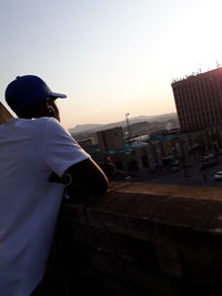 Rear view of man standing in city against clear sky