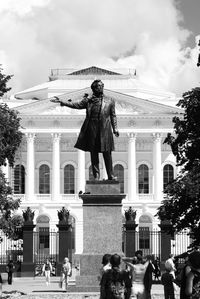 Statue of people outside building against sky