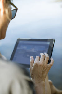 Cropped image of mid adult woman using digital tablet outdoors