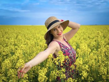Beautiful young woman standing by yellow flower in field