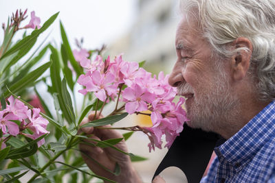 Close-up of senior man smelling flower outdoors