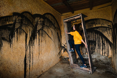 Side view of young woman standing in wood frame against wall in old room