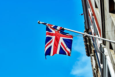Low angle view of flag against building against clear blue sky