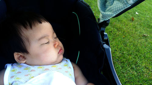 Close-up high angle view of cute toddler sleeping in baby stroller outdoors