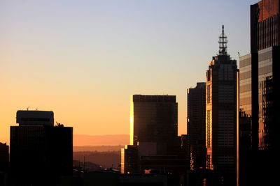 Silhouette buildings against clear sky during sunset