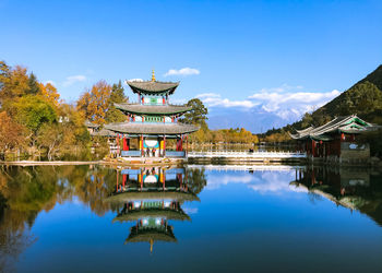 Traditional building by lake against sky