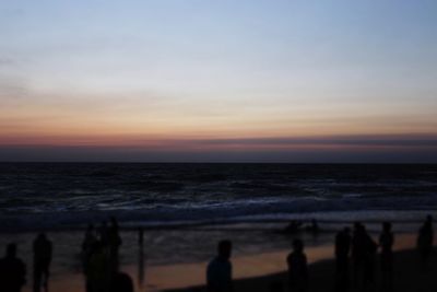 Silhouette people on beach against sky during sunset